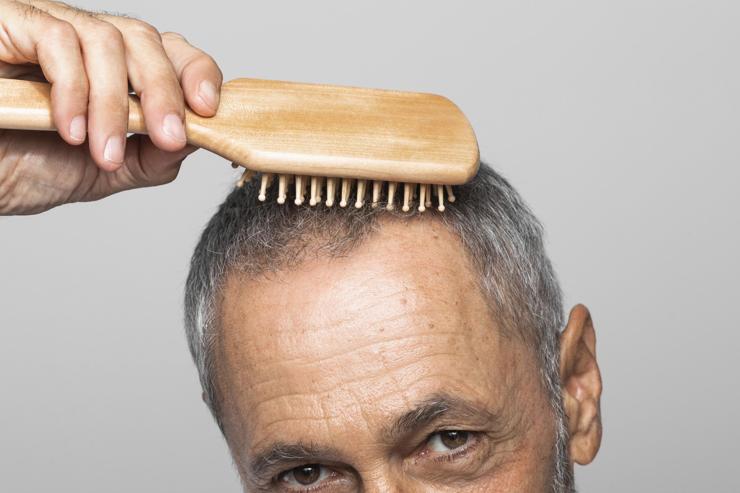 close up man brushing thinning hair